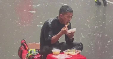 رجل إطفاء يتناول طعامه تحت المطر خلال إنقاذ ضحايا الفيضانات فى الصين